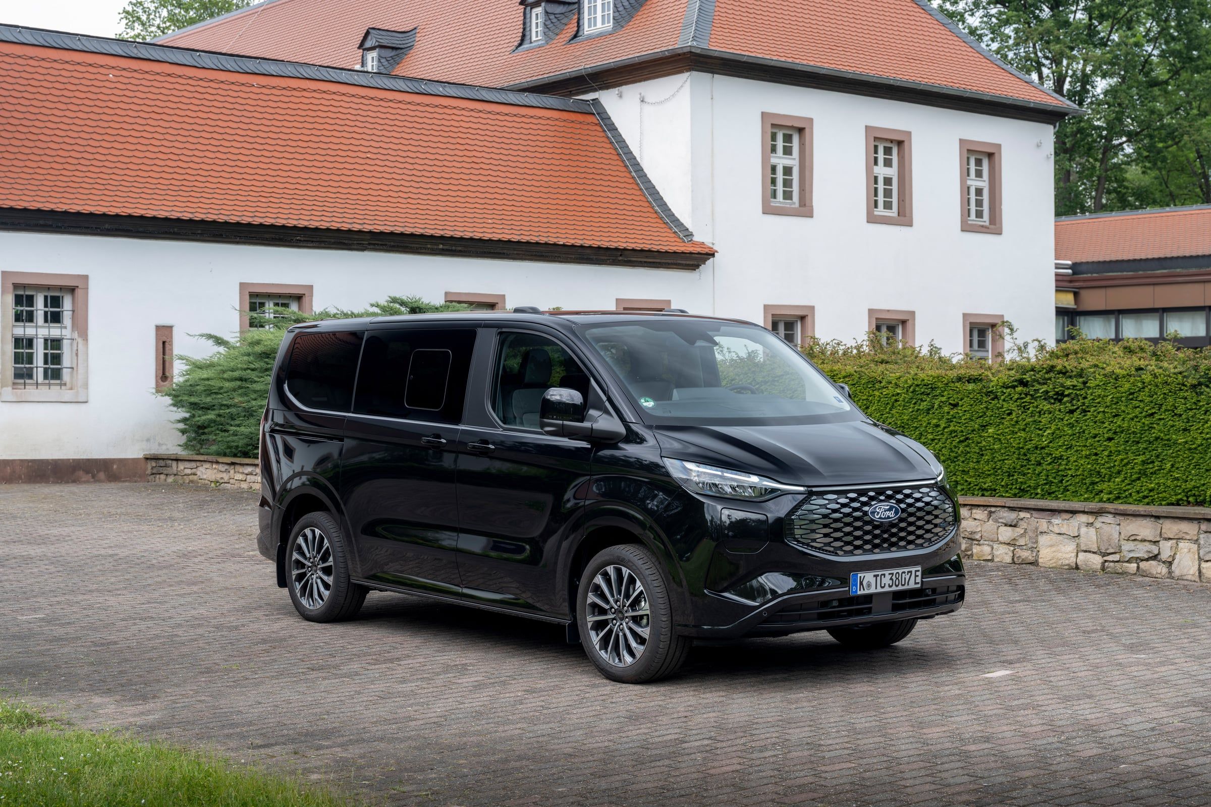 A black Ford Tourneo Custom parked on a cobbled courtyard, seen from the front corner.